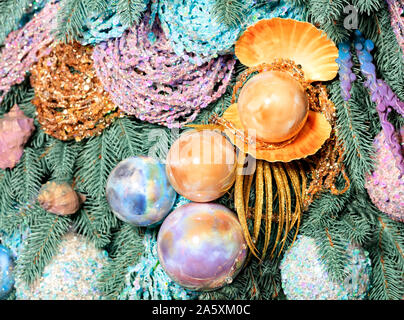 Grandes boules de perles d'or, de teinte rose et bleu sont accrochées sur les branches décoratives de l'arbre de Noël. Décorations de Nouvel An sea marine des symboles. Banque D'Images