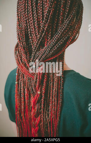 Coiffure africaine sur une fille d'apparence, cheveux de couleur rouge, beaucoup de tresses fines Banque D'Images