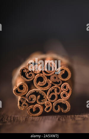 Les bâtons de cannelle Vue de face close-up. Les bâtons sont attachés ensemble, l'accent est mis sur l'accumulation se termine, et le fond sombre est floue. Banque D'Images