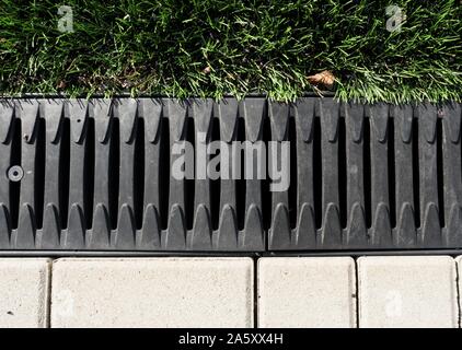 Les systèmes de drainage. Robinets de tempête. La construction de béton et de métal entre la chaussée et le vert. Grille d'égout et sur le terrain pour évacuer l'eau libre. Banque D'Images