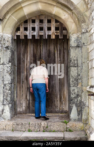 Nosey femme..à la recherche à travers les fissures de la porte médiévale. Les murs de la ville de Southampton England UK Banque D'Images