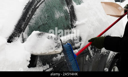 Efface l'homme voiture de neige sur une froide journée d'hiver après la neige. Pinceau en main. mans Beaucoup de neige sur la voiture. Banque D'Images