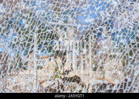 Surface de verre cassée avec jardin contexte en bas. Double couche, surface en verre de sécurité trempé avec de petits morceaux de verre visible Banque D'Images