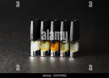 E-vape jus pods de remplissage avec des liquides de différentes nuances de jaune, orange isolé sur fond noir close up Banque D'Images