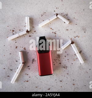 Vape rouge unique cigarette électronique comme alternative de fumer des cigarettes et de tabac épars sur fond texturé blanc isolé Banque D'Images