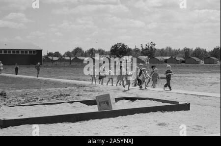 Comté de Tulare, en Californie. Farm Security Administration (FSA) camp pour les travailleurs migrants du secteur agricole. Les enfants d'école maternelle. Rangée d'abris préfabriqués en acier dans lequel vivent leurs familles illustré en arrière-plan par Dorothea Lange 1895-1965, en date du 19380101 Banque D'Images