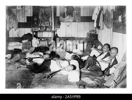 L'opium den sur rue Malinta, Manille, Philippines. La photo montre l'intérieur d'un opium den avec plusieurs hommes, inclinables fumeurs d'opium depuis longtemps les tuyaux. . 1924. Banque D'Images