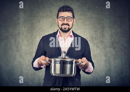 Happy handsome man with cooking pot looking at camera Banque D'Images