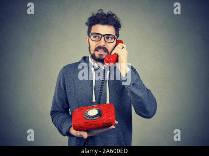 L'homme irrité en conversation sur un téléphone à l'ancienne, mécontents de longue attente pour le service à la clientèle Banque D'Images