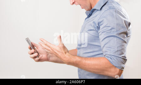 Homme inconnu tenant son smart phone hurler de frustration à de mauvaises nouvelles.. Banque D'Images