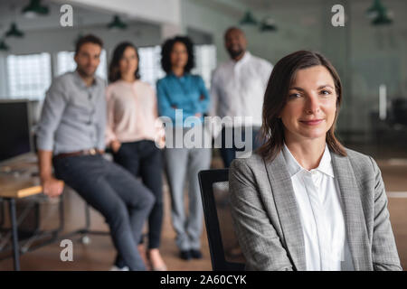 Businesswoman smiling with coworkers debout dans l'arrière-plan Banque D'Images