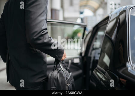 La mi-section of businessman entrer dans un taxi Banque D'Images