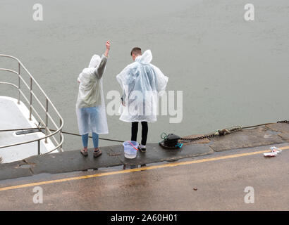 Deux jeunes gens de la pêche du crabe dans la pluie Banque D'Images