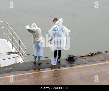 Deux jeunes gens de la pêche du crabe dans la pluie Banque D'Images