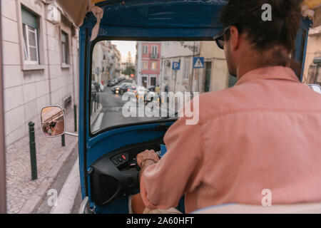 Vue de derrière d'un tuk tuk driver dans la ville, Lisbonne, Portugal Banque D'Images