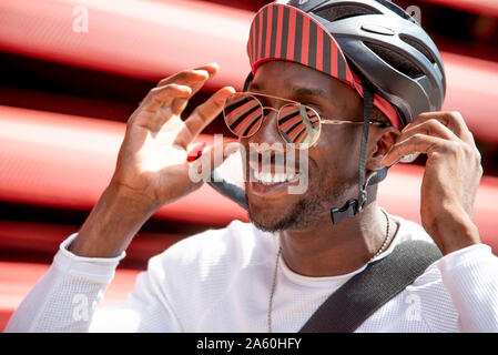 Smiling young man putting sur son casque de vélo Banque D'Images