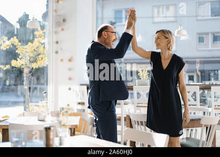 Homme et femme haut-fiving dans un coffee shop Banque D'Images
