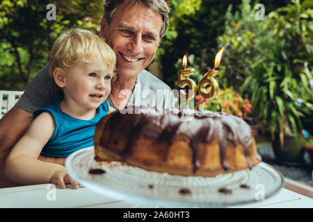 Petit garçon assis sur les genoux du père, qui fête son anniversaire