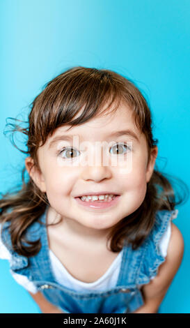 Portrait of cute little girl smiling très expressifs sur fond bleu Banque D'Images