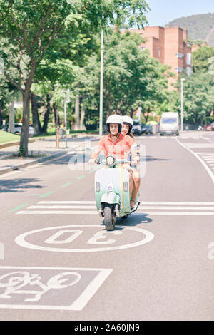 Jeune couple vintage scooter sur route urbaine Banque D'Images