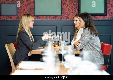 Trois businesswomen talking tandis que manger ensemble dans un restaurant. Banque D'Images
