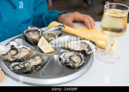 Un close up of delicious des huîtres sur écailles avec un verre de vin blanc français Banque D'Images