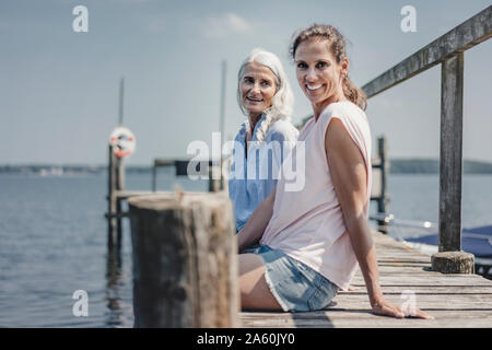 Mother and Daughter sitting on Jetty, détente à la mer Banque D'Images