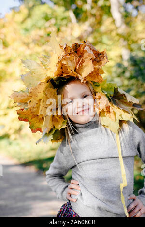 Portrait of smiling little girl avec sur sa tête une couronne d'automne Banque D'Images