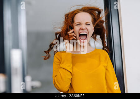 Screaming woman with windswept hair in office Banque D'Images