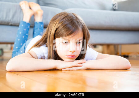Portrait de jeune fille triste se trouvant sur le plancher à la maison Banque D'Images