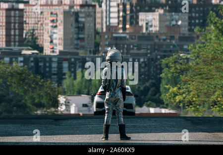 Vue arrière du garçon habillé comme un astronaute debout sur une rue de la ville Banque D'Images