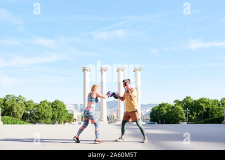 Entraîneur de boxe fitness pratique classe avec jeune femme à l'extérieur dans la ville Banque D'Images