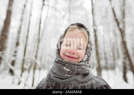 Portrait of happy little girl wearing headscarf en forêt d'hiver Banque D'Images