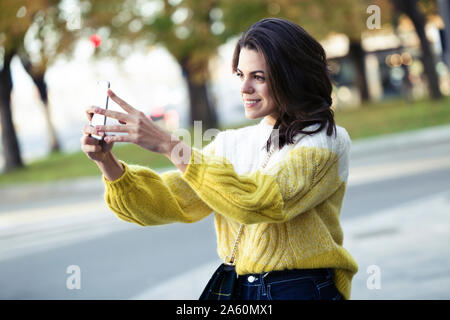 Brunette woman taking a dans la ville selfies Banque D'Images