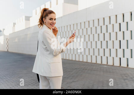 Pantalon blanc femme en costume, using smartphone Banque D'Images