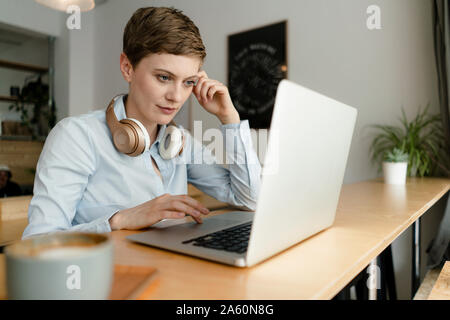 Businesswoman using laptop avec un casque dans un café Banque D'Images