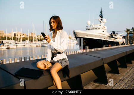 Jolie man à la marina après le travail, using smartphone Banque D'Images
