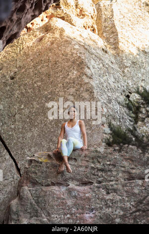 Young Asian woman sitting on a rock