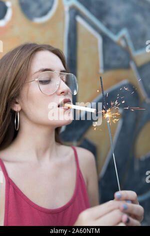 Jeune femme avec une cigarette d'éclairage sparkler Banque D'Images