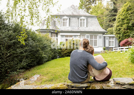 Vue arrière du couple assis sur un mur de jardin Banque D'Images