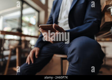 Close-up of businessman holding cell phone in a cafe Banque D'Images