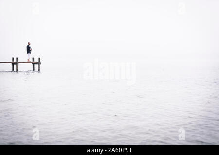 Barefoot man meditating on jetty au Lac de Starnberg, Allemagne Banque D'Images