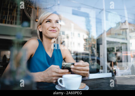 Businesswoman Taking a break in coffee shop, holding smartphone Banque D'Images