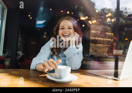 Portrait de femme rousse heureux avec un ordinateur portable dans un café Banque D'Images