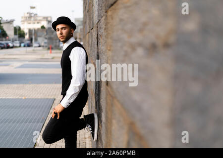 Portrait de jeune homme habillé en noir et blanc leaning against wall Banque D'Images