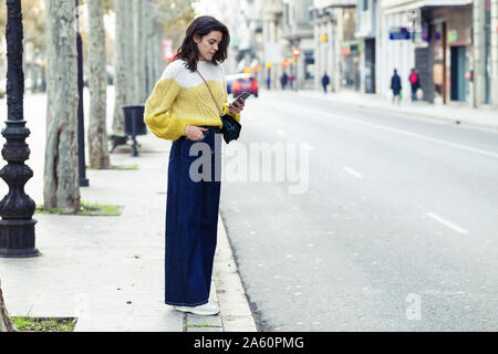 Brunette woman en utilisant son smartphone dans la ville Banque D'Images