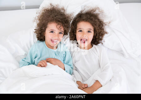 Portrait de deux frères jumeaux heureux au lit Banque D'Images