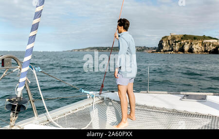 Jeune homme debout sur un voilier Banque D'Images