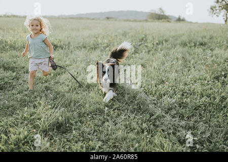 Fille courir avec chien sur un pré à la campagne Banque D'Images