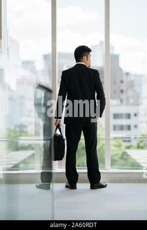 Young businessman looking out of window Banque D'Images